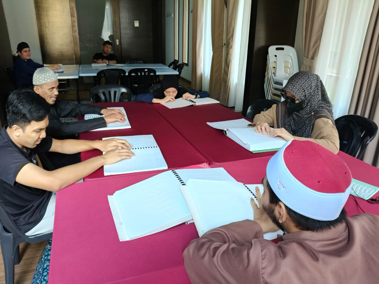 Ahli-ahli PERTIS duduk mengelilingi meja membaca naskhah Al-Quran Braille dalam kelas SAQB