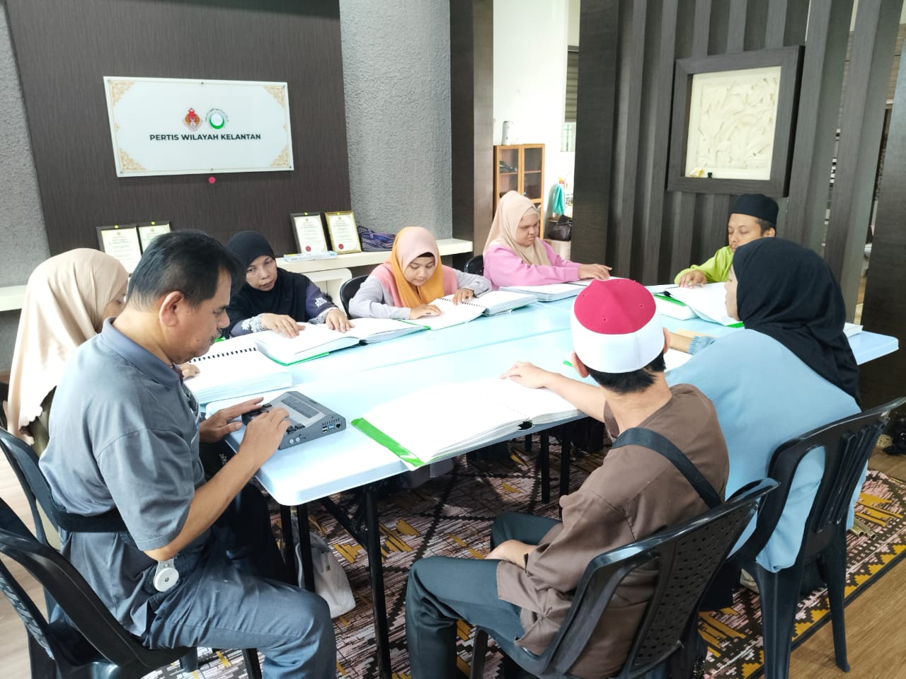 Ahli PERTIS Wilayah Kelantan berkumpul membaca Al-Quran Braille di ruang pejabat persatuan
